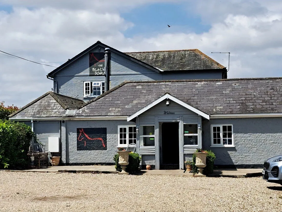 The front of the main house: pale render, slate roof, a black board with the red donkey sign, and a gravel forecourt.